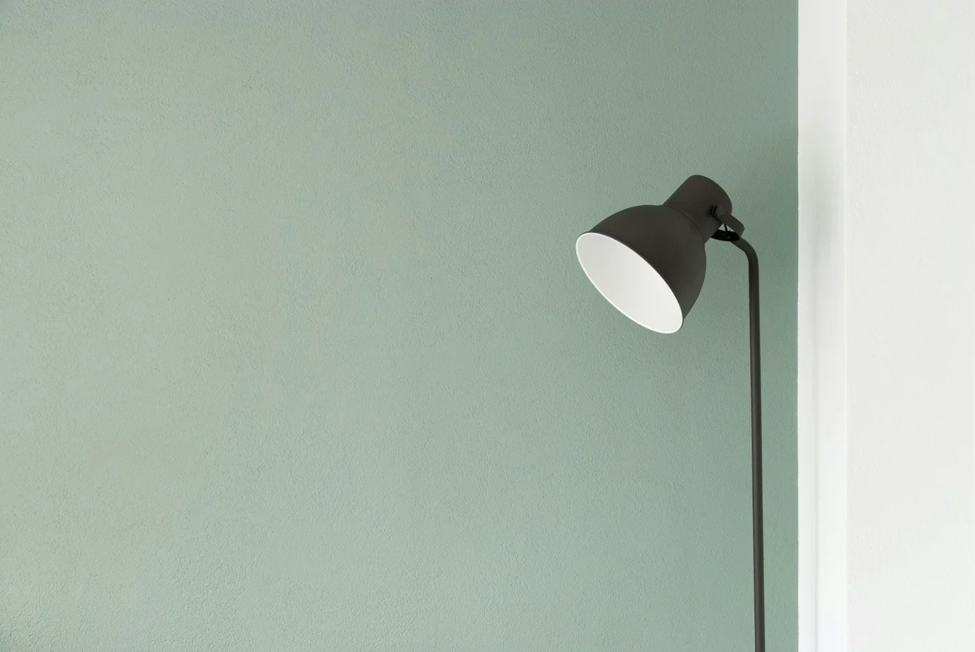 A floor lamp against a muted green wall
