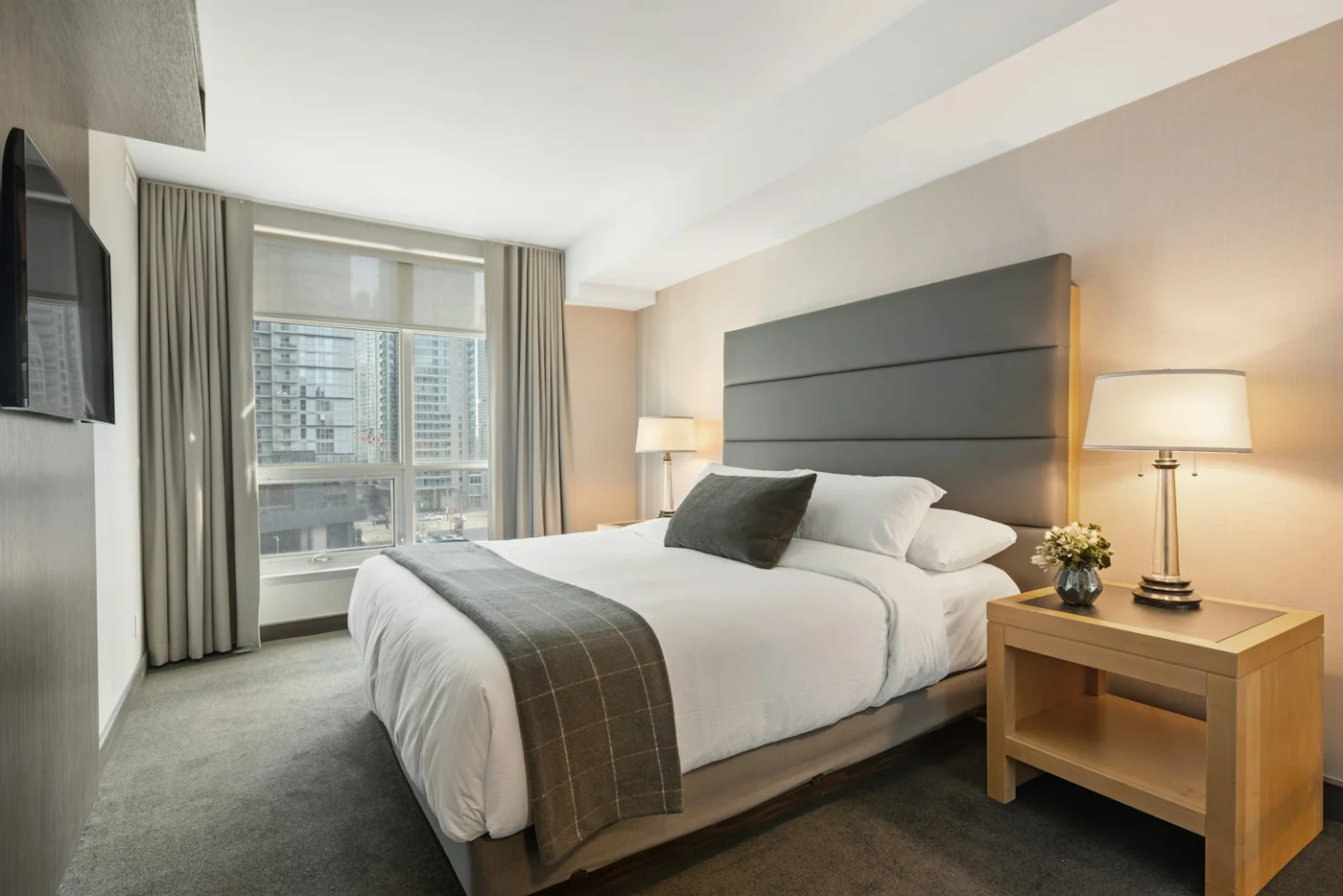 A neatly made bed with soft neutral bedding