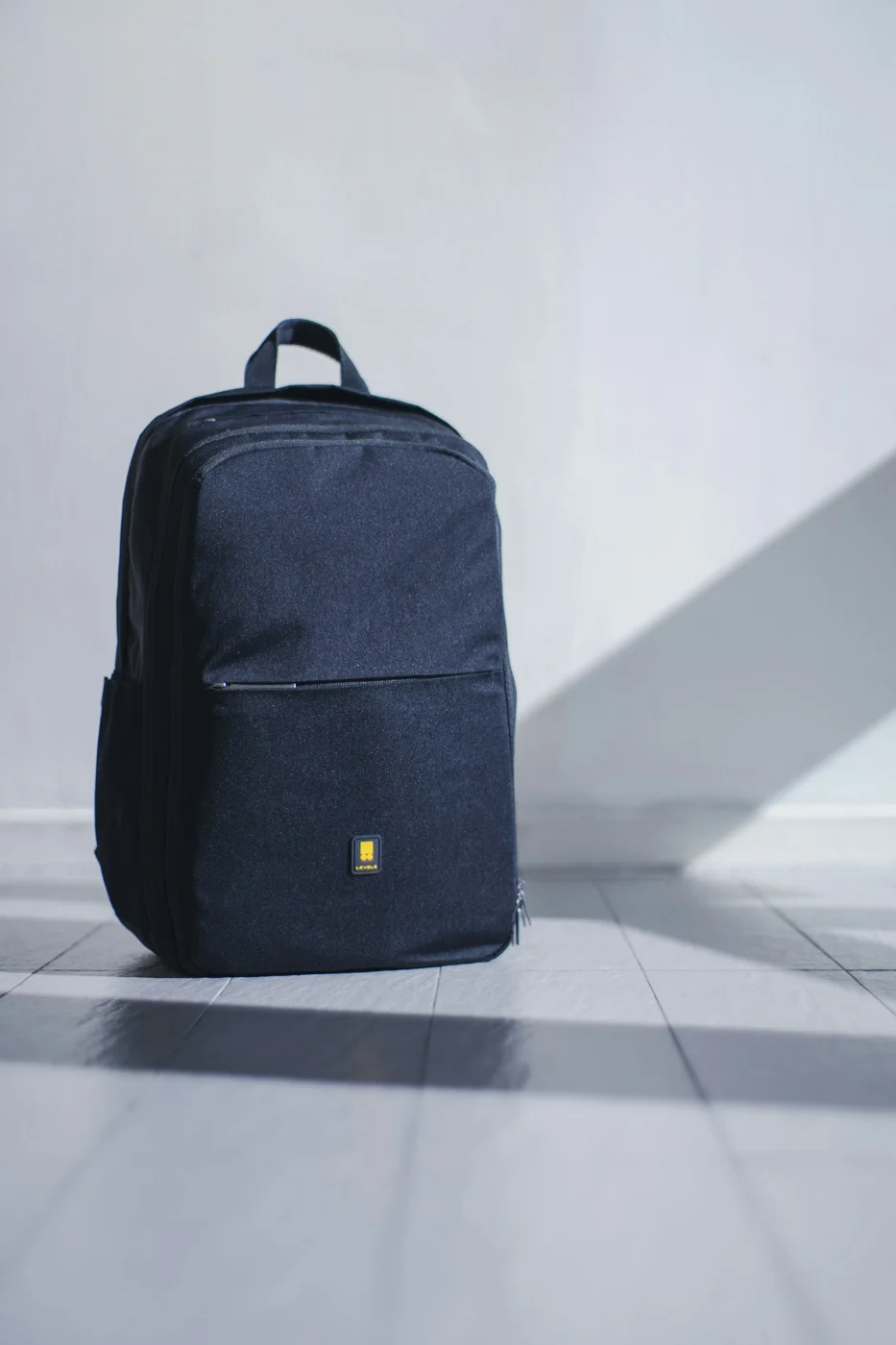 A simple dark backpack resting against a wall