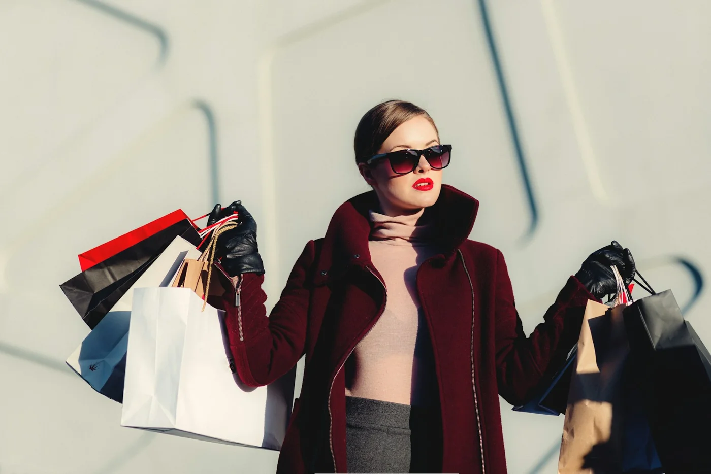 A woman wearing sunglasses and a scarf with shopping bags